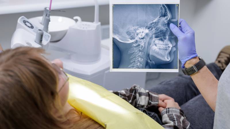 Dental professional holding Xray to show the patient how airway-focused orthodontics supports healthy facial structure and jaw development.