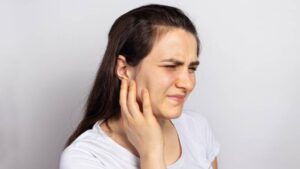 Person holding their jaw, illustrating common symptoms of TMD and facial pain.