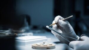 Dental technician precisely crafting a metal-free ceramic crown, emphasizing the precise, custom nature of holistic dental care.